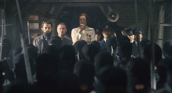 Movie still from “Snowpiercer” (2013), directed by Bong Joon Ho – A group of people standing around a crowd of people; Medium shot, Low angle