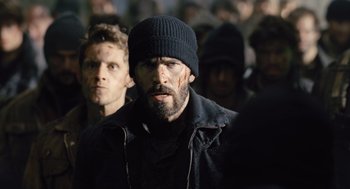 Movie still from “Snowpiercer” (2013), directed by Bong Joon Ho – A man in a black jacket and a black hat; Medium shot, Low angle