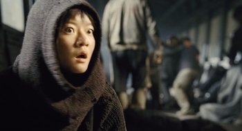 Movie still from “Snowpiercer” (2013), directed by Bong Joon Ho – A young woman in a hooded jacket looking at the camera; Close Up shot, Low angle