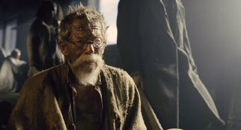 Movie still from “Snowpiercer” (2013), directed by Bong Joon Ho – An old man with a long beard wearing glasses; Close Up shot, Over the shoulder angle