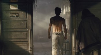 Movie still from “Snowpiercer” (2013), directed by Bong Joon Ho – A man walking through a doorway in a room; Medium shot, Low angle