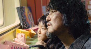 Movie still from “Snowpiercer” (2013), directed by Bong Joon Ho – A man and a woman sitting next to each other at a table; Close Up shot, Over the shoulder angle