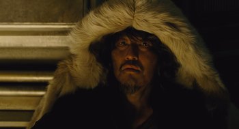Movie still from “Snowpiercer” (2013), directed by Bong Joon Ho – A man wearing a fur hat and a black jacket; Close Up shot, Low angle