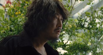Movie still from “Snowpiercer” (2013), directed by Bong Joon Ho – A person wearing a black shirt near a tree; Close Up shot, Low angle