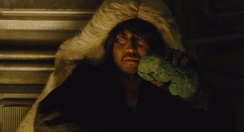 Movie still from “Snowpiercer” (2013), directed by Bong Joon Ho – A man in a fur hat holding a piece of broccoli; Close Up shot, Overhead angle