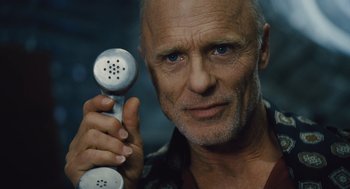 Movie still from “Snowpiercer” (2013), directed by Bong Joon Ho – An older man holding a phone up to his ear; Close Up shot, Low angle