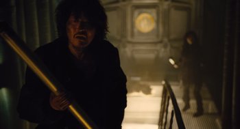 Movie still from “Snowpiercer” (2013), directed by Bong Joon Ho – A man holding a stick in a dark room; Medium shot, Low angle