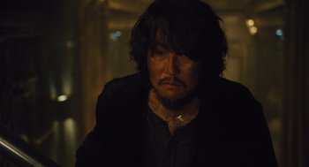 Movie still from “Snowpiercer” (2013), directed by Bong Joon Ho – A man with long hair and a beard is looking at the camera; Close Up shot, High angle