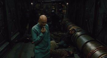 Movie still from “Snowpiercer” (2013), directed by Bong Joon Ho – A man standing next to a bunch of corpses in a room; Wide shot, High angle