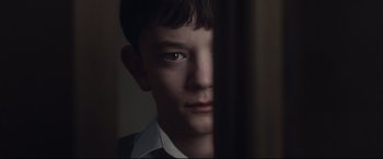 Movie still from “A Monster Calls” (2016), directed by J.A. Bayona – A young man with a green eye stares into the camera; Close Up shot, High angle