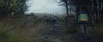 Movie still from “A Monster Calls” (2016), directed by J.A. Bayona – An iron gate in the middle of a grassy field; Extreme Wide shot, High angle
