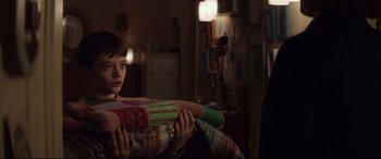 Movie still from “A Monster Calls” (2016), directed by J.A. Bayona – A boy holding a blanket in a room; Medium shot, Over the shoulder angle