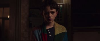 Movie still from “A Monster Calls” (2016), directed by J.A. Bayona – A young boy wearing a colorful sweater in a dark room; Close Up shot, Over the shoulder angle