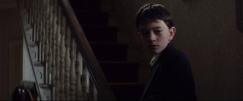 Movie still from “A Monster Calls” (2016), directed by J.A. Bayona – A young man in a suit standing next to a staircase; Close Up shot, Low angle