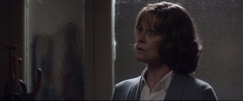 Movie still from “A Monster Calls” (2016), directed by J.A. Bayona – A woman in a white shirt and a gray jacket looking out a window; Close Up shot, Over the shoulder angle