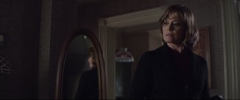 Movie still from “A Monster Calls” (2016), directed by J.A. Bayona – A woman standing in front of a mirror in a room; Medium shot, Over the shoulder angle