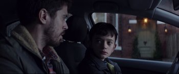 Movie still from “A Monster Calls” (2016), directed by J.A. Bayona – A man and a boy sitting in a car looking at each other; Close Up shot, Over the shoulder angle