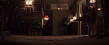 Movie still from “A Monster Calls” (2016), directed by J.A. Bayona – A person standing in a room with a lamp; Wide shot, Low angle