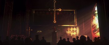 Movie still from “A Monster Calls” (2016), directed by J.A. Bayona – A man standing in front of a cross on a stage; Extreme Wide shot, Low angle