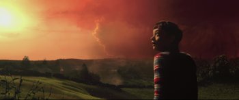 Movie still from “A Monster Calls” (2016), directed by J.A. Bayona – A young child standing in front of an orange sky; Medium shot, Low angle