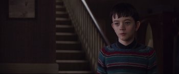 Movie still from “A Monster Calls” (2016), directed by J.A. Bayona – A young boy standing in front of a staircase; Medium shot, Low angle