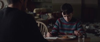 Movie still from “A Monster Calls” (2016), directed by J.A. Bayona – A boy sitting at a table with a plate of food; Medium shot, Over the shoulder angle