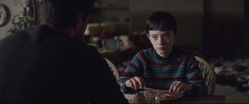 Movie still from “A Monster Calls” (2016), directed by J.A. Bayona – A boy sitting at a table with a plate of food in front of him; Medium shot, Over the shoulder angle