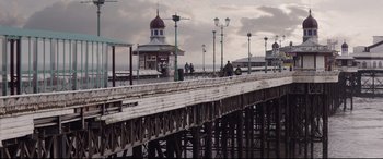Movie still from “A Monster Calls” (2016), directed by J.A. Bayona – People are standing on a pier near the water; Extreme Wide shot, Low angle