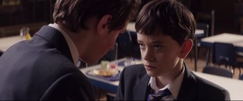 Movie still from “A Monster Calls” (2016), directed by J.A. Bayona – Two young men in suits talking to each other; Close Up shot, Over the shoulder angle