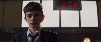 Movie still from “A Monster Calls” (2016), directed by J.A. Bayona – A boy in a suit and tie standing in front of a clock; Close Up shot, Low angle