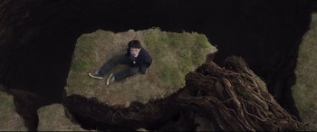 Movie still from “A Monster Calls” (2016), directed by J.A. Bayona – A man laying on the ground in the middle of a field; Wide shot, Overhead angle