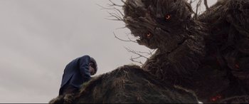 Movie still from “A Monster Calls” (2016), directed by J.A. Bayona – A man standing on top of a hill next to a tree; Wide shot, Low angle