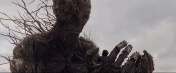 Movie still from “A Monster Calls” (2016), directed by J.A. Bayona – A man sitting on top of a tree; Wide shot, Low angle