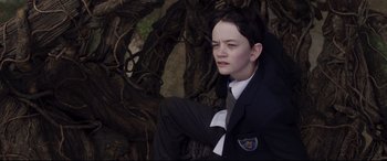 Movie still from “A Monster Calls” (2016), directed by J.A. Bayona – A boy in a suit sitting in front of a tree; Medium shot, High angle