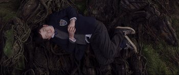Movie still from “A Monster Calls” (2016), directed by J.A. Bayona – A man laying on the ground wearing a suit and tie; Wide shot, Overhead angle