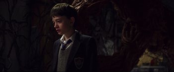Movie still from “A Monster Calls” (2016), directed by J.A. Bayona – A boy in a suit and tie standing in front of a tree; Medium shot, Over the shoulder angle