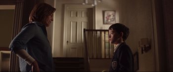 Movie still from “A Monster Calls” (2016), directed by J.A. Bayona – A boy and a girl are standing in a living room; Medium shot, Low angle