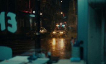 Movie still from “So Long, Stooge” (1983), directed by Claude Berri – A car driving down the street in the rain at night; Wide shot, Over the shoulder angle