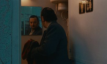 Movie still from “So Long, Stooge” (1983), directed by Claude Berri – A man looking in the mirror in front of a bathroom mirror; Medium shot, Over the shoulder angle