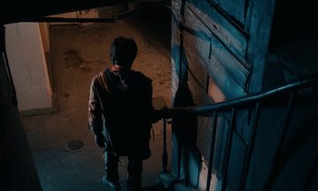 Movie still from “So Long, Stooge” (1983), directed by Claude Berri – A man with a backpack walking up a ramp; Wide shot, High angle