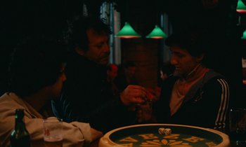 Movie still from “So Long, Stooge” (1983), directed by Claude Berri – A group of people sitting at a table playing a game; Medium shot, High angle