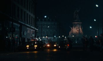 Movie still from “So Long, Stooge” (1983), directed by Claude Berri – A city street at night lit up by streetlights; Extreme Wide shot, High angle