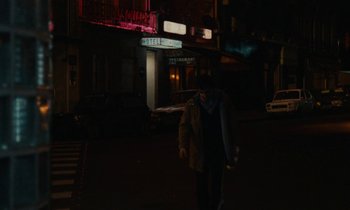 Movie still from “So Long, Stooge” (1983), directed by Claude Berri – A man walking down a street at night; Wide shot, Over the shoulder angle