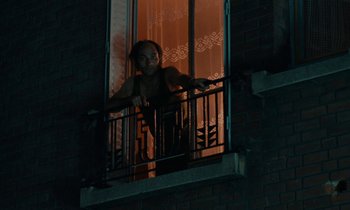 Movie still from “So Long, Stooge” (1983), directed by Claude Berri – A woman standing on a balcony at night looking out of a window; Medium shot, Low angle
