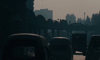 Movie still from “So Long, Stooge” (1983), directed by Claude Berri – Cars are driving down the street in the dark; Extreme Wide shot, High angle