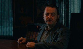 Movie still from “So Long, Stooge” (1983), directed by Claude Berri – A man sitting at a table in front of a window; Close Up shot, Low angle