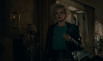 Movie still from “So Long, Stooge” (1983), directed by Claude Berri – A woman in a leather jacket smoking a cigarette in a dark room; Medium shot, Over the shoulder angle