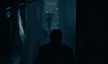 Movie still from “So Long, Stooge” (1983), directed by Claude Berri – A man is walking down a dark alley way; Wide shot, High angle