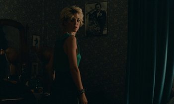 Movie still from “So Long, Stooge” (1983), directed by Claude Berri – A woman standing in a dark room looking at the camera; Medium shot, Over the shoulder angle