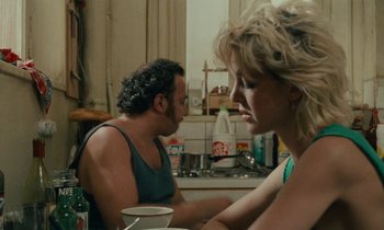 Movie still from “So Long, Stooge” (1983), directed by Claude Berri – A man and a woman sitting at a table in a kitchen; Medium shot, Over the shoulder angle